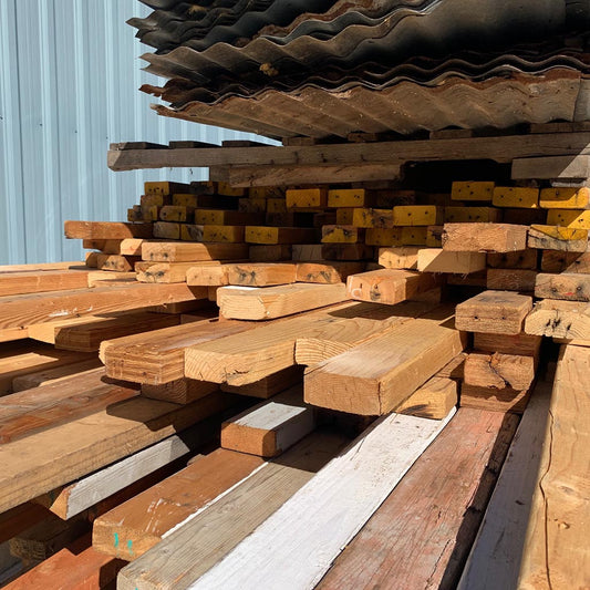 Stack of wooden planks and metal sheets against a blue wall.